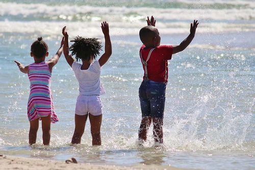 Three little kids playing in the water of one of the beaches in South Africa