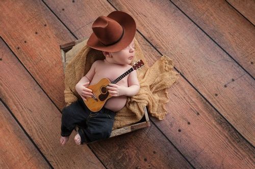A newborn baby sleeping with a guitar and cowboy hat