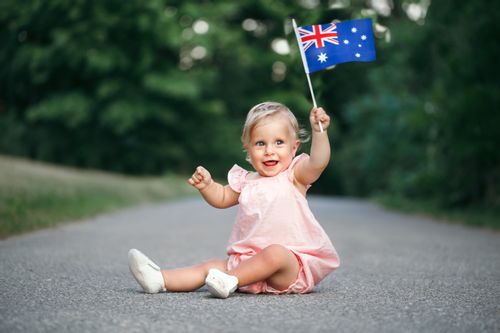 A baby girl holding Australian flag in her hand