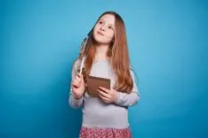  Petite fille tenant un stylo et du papier pensant à l'Angleterre anglo-saxonne.