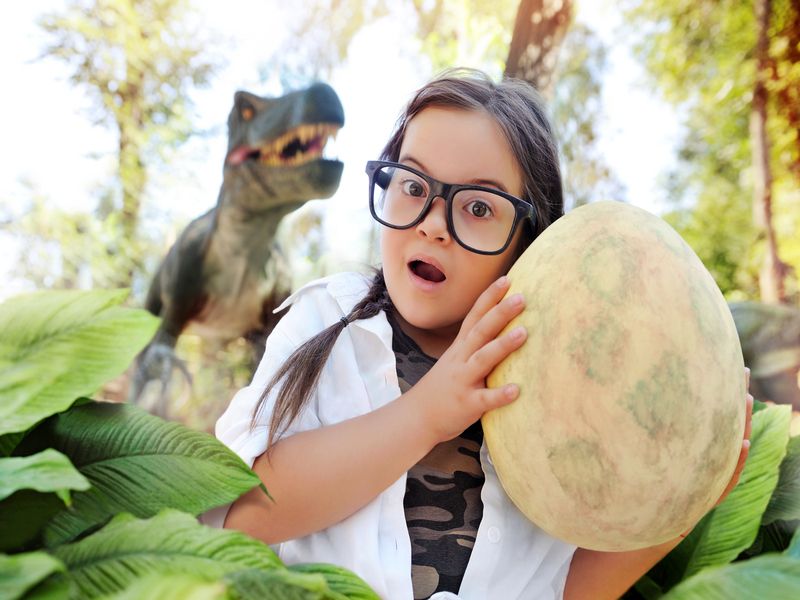 Little girl holding dinosaur egg in hands.